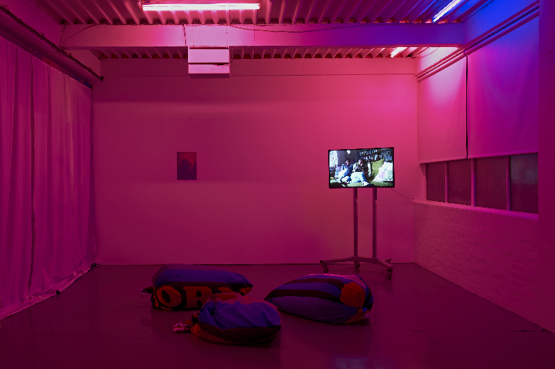 Pink image of screen on a stand, beanbag seating and photograph pinned on the back wall