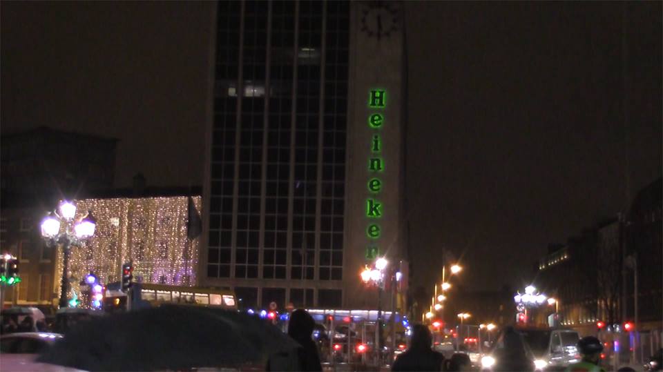 A night city view with a prominent green glowing Heineken logo