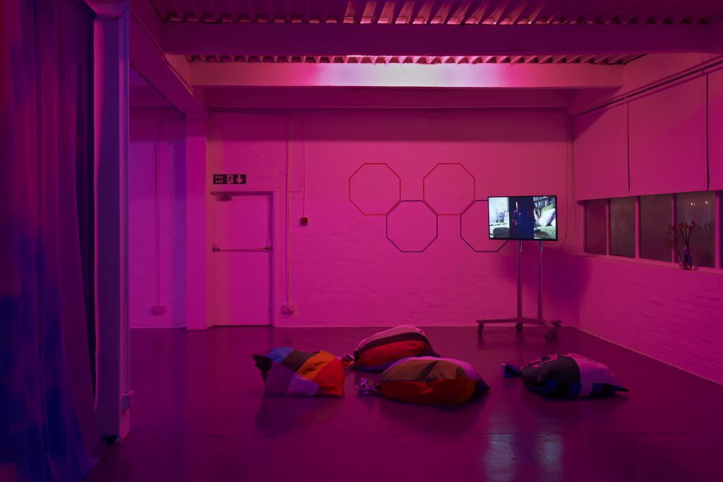 Pink image of screen on a stand, beanbag seating and hexagonal wall painting