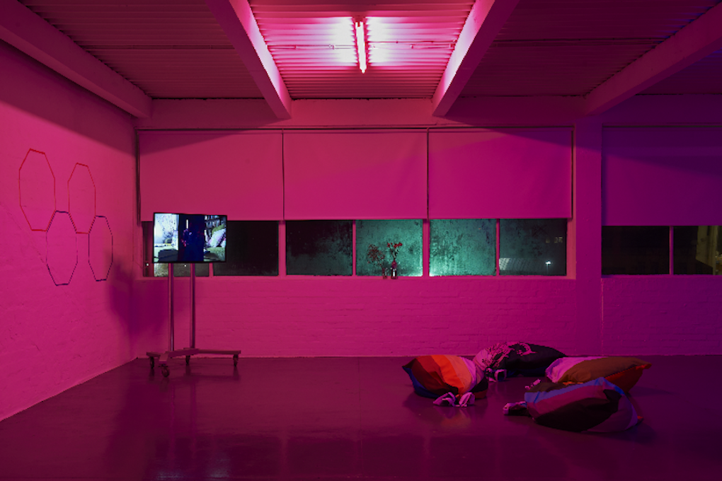 Pink image of screen on a stand, beanbag seating and hexagonal wall painting