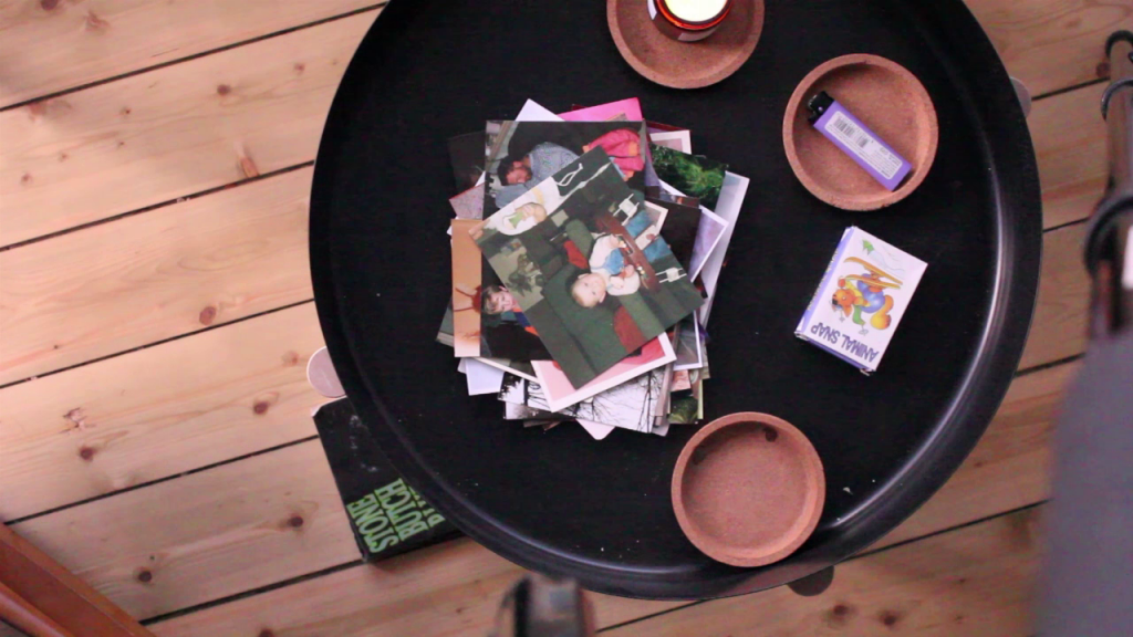 detritus on a coffee table including a stack of photos with a copy of Stone Butch Blues visible below 