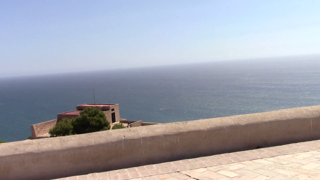 blue sea towards a blue horizon with a stone wall in the foreground