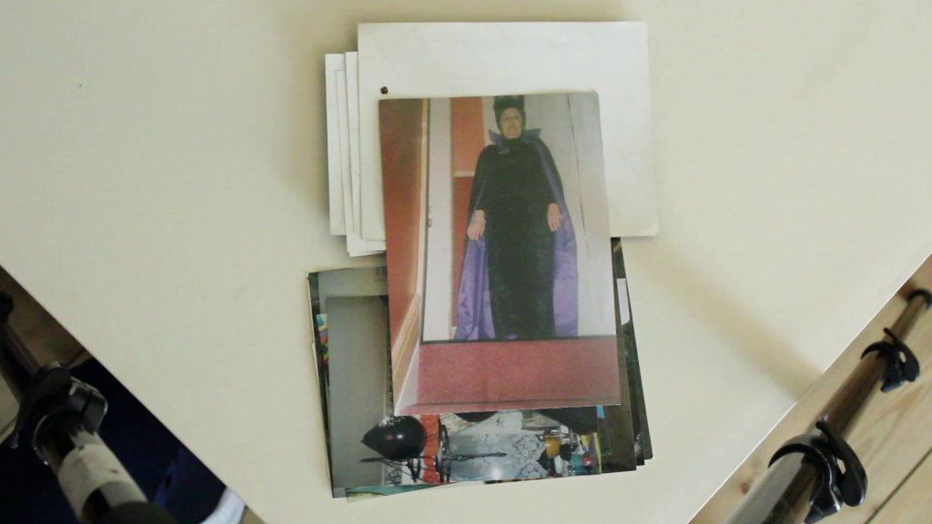 two piles of photos, face up and face down, with a photo of a woman dressed as a witch laid over the top, on a white table