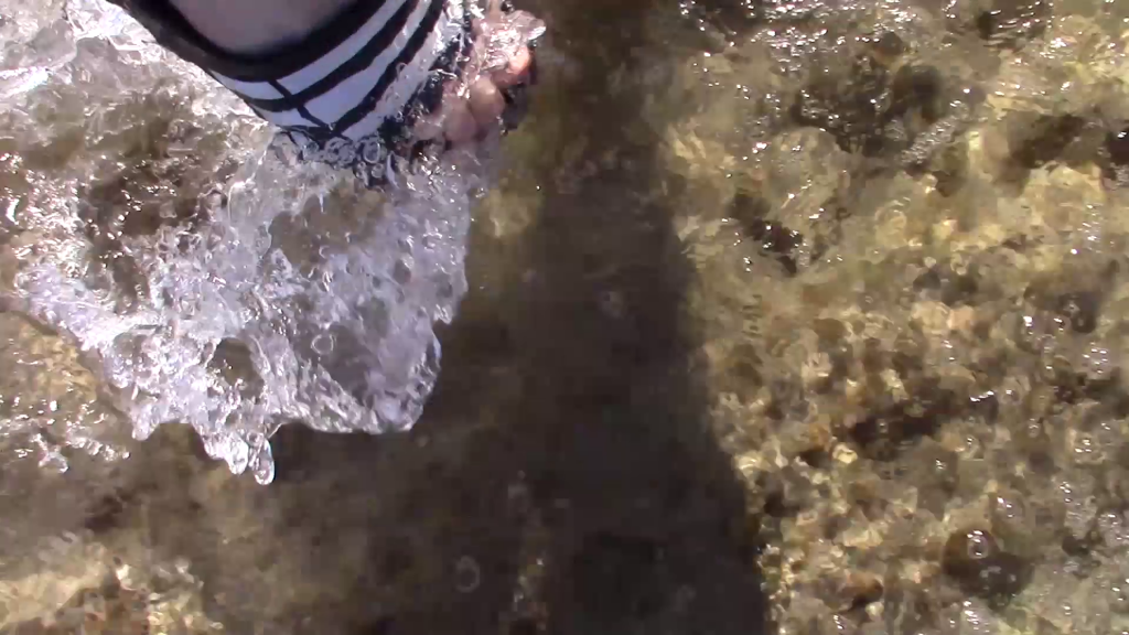 foot with a black and white Adidas slider emerging from the sea 