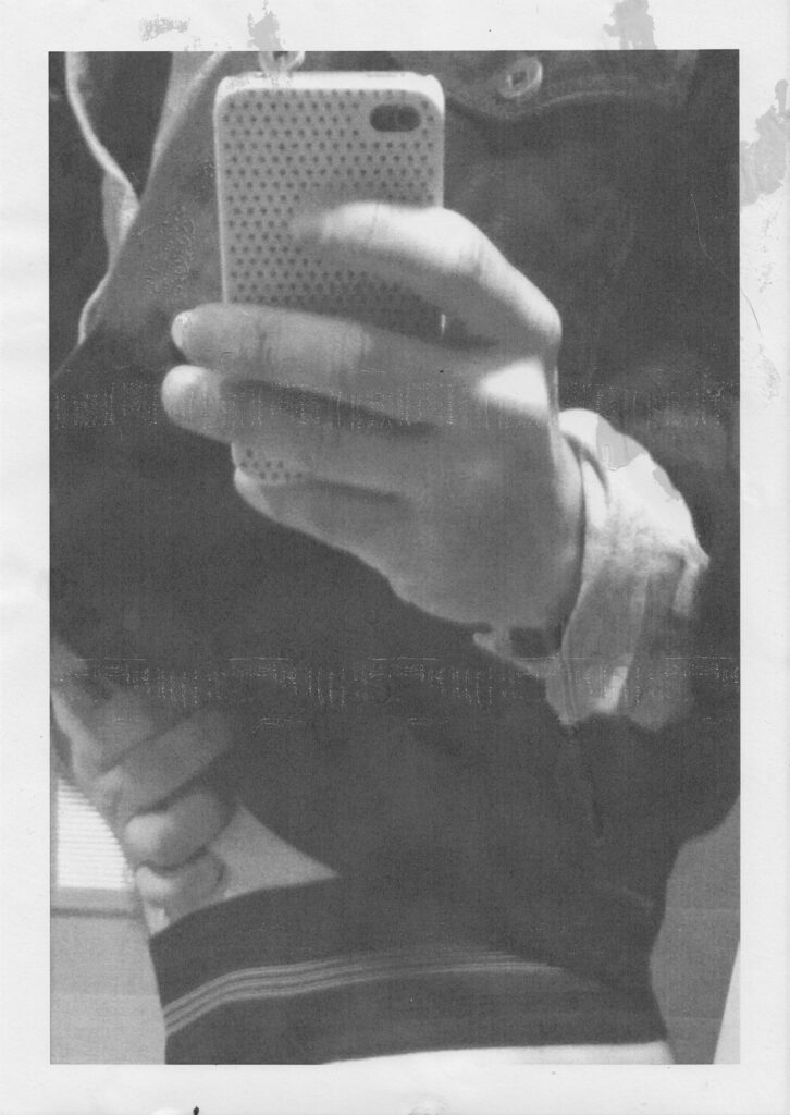 scanned and dirtied printout of photo of hand holding a phone taking a selfie 