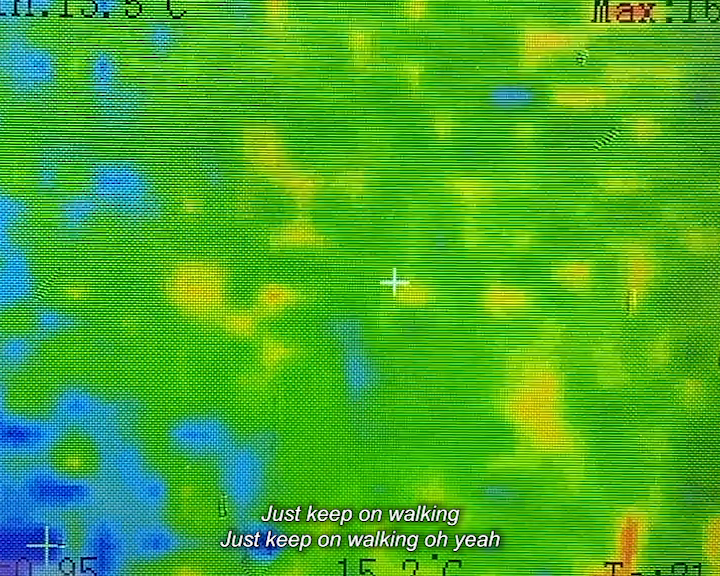 Colourful thermal map with green, yellow, blue, and orange tones, featuring a white crosshair in the centre. Caption reads ‘Just keep on walking, Just keep on walking oh yeah ‘.